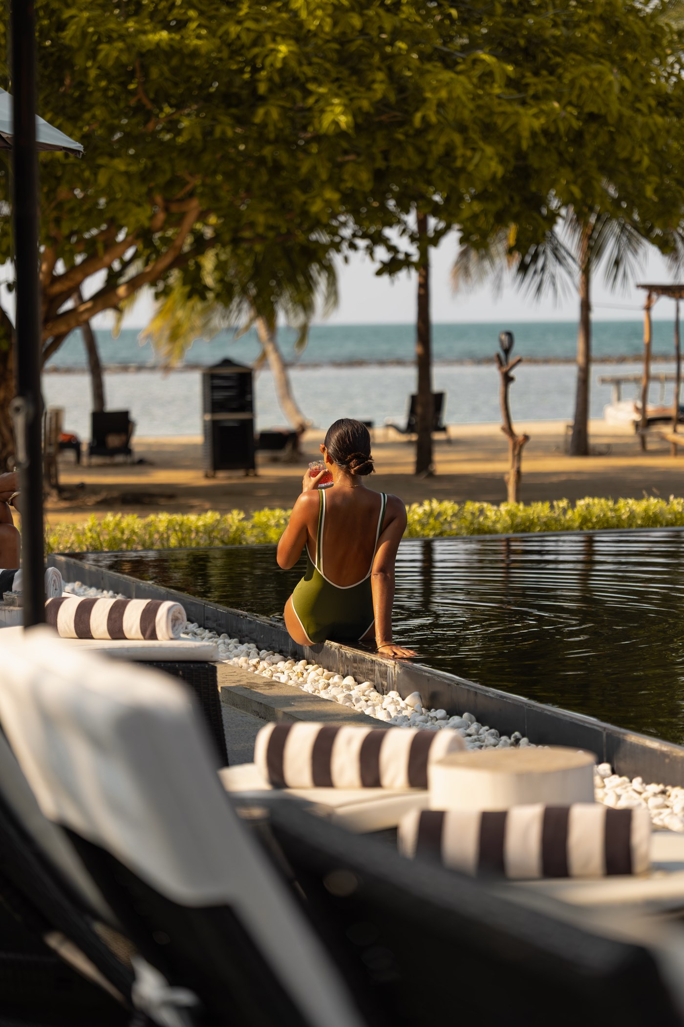 A guest at the edge of the infinity pool looking across the beach to the sea