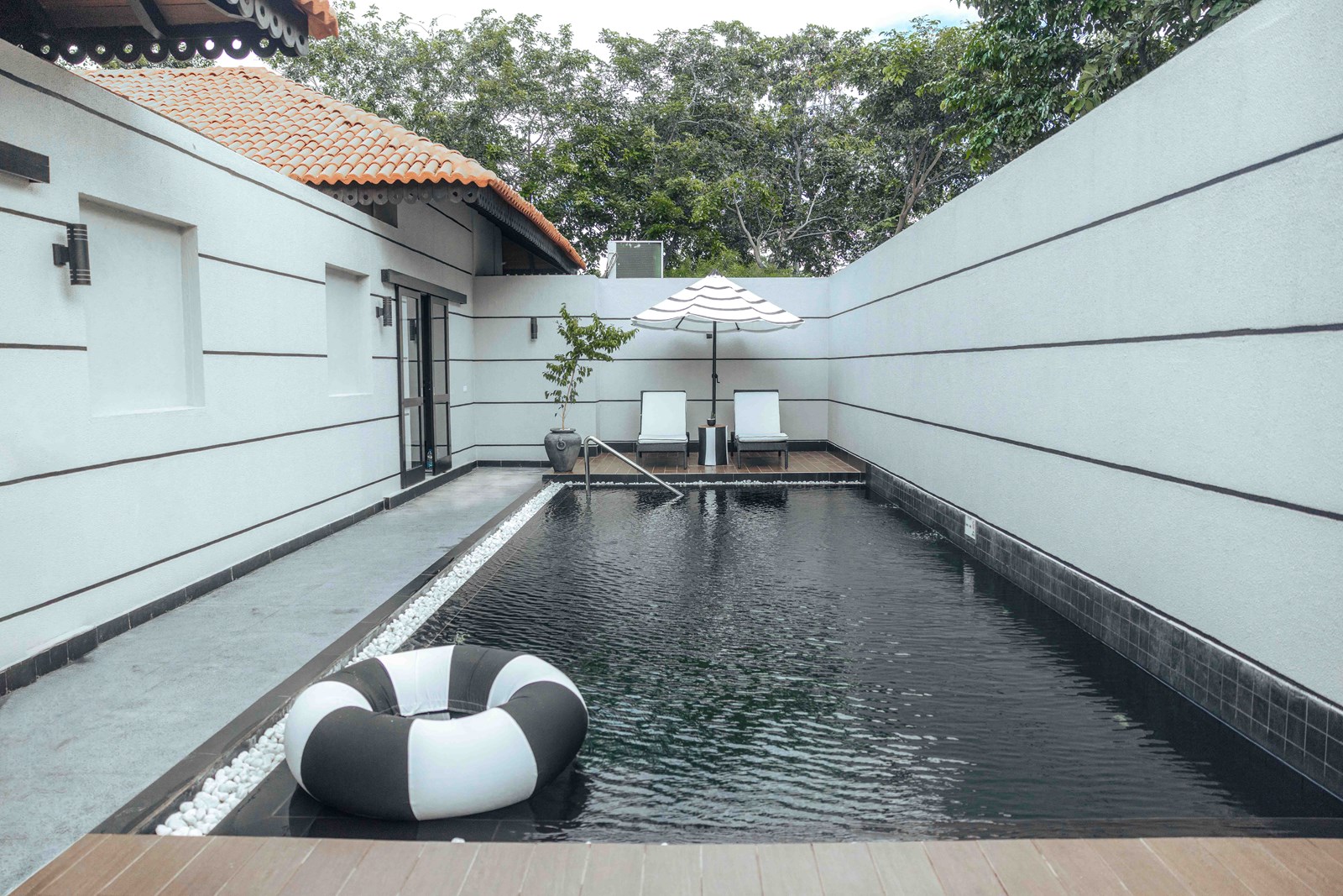 The villa's long dark pool in a walled courtyard with loungers and a parasol